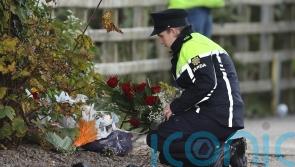 Groups huddle together as family and friends lay floral tributes in Creeslough