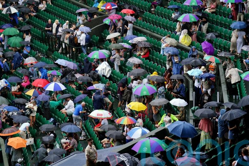 Tennis fans in macs and under umbrellas in queue for Wimbledon’s middle Sunday